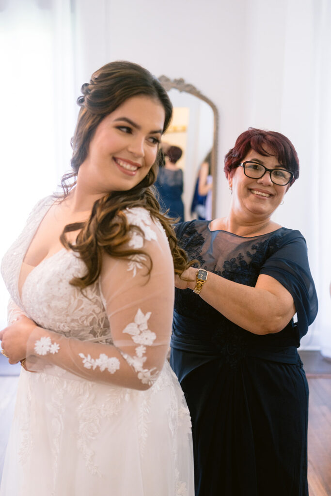 bride having her dress fastened by her mother on her wedding day at Bella Cosa Estate in Lake Wales, photographed by her Sarasota wedding photographer