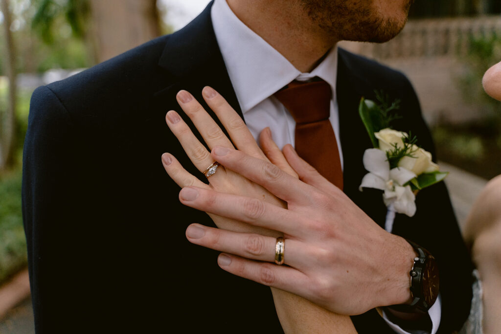 bride and groom with their hands together showing their wedding rings at their Sarastoa wedding at New College